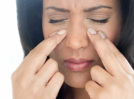 A black lady with her fingers on her cheeks presumably in pain from CRS.